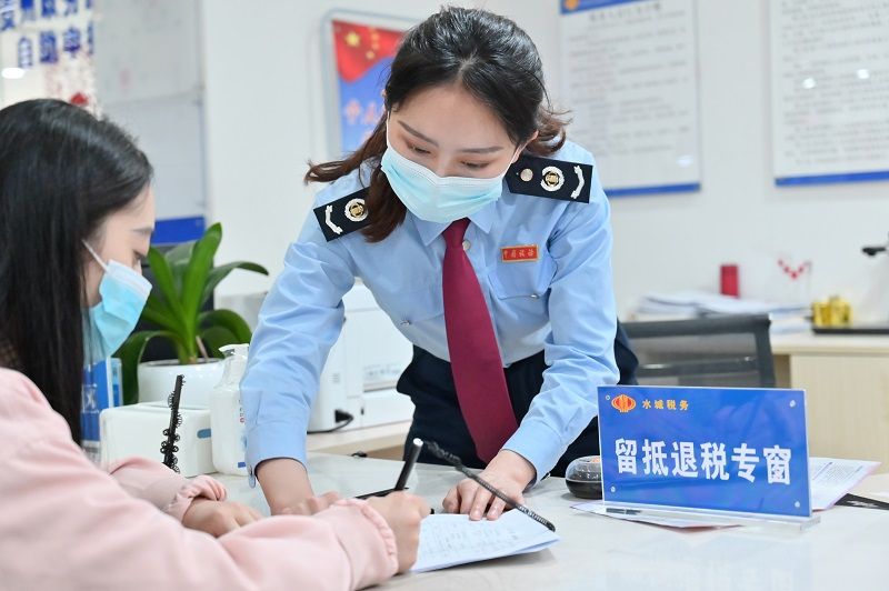 水城区税务局窗口工作人员正在辅导纳税人填写资料。（张定国摄）.jpg